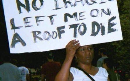 2005 жылы Вашингтонда Ирактағы соғысқа қарсы митингте әйел "Катрина" дауылынан кейінгі трагедия туралы плакат ұстап тұр.